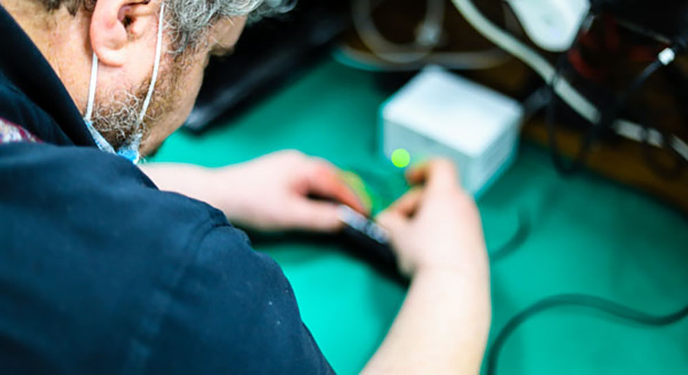 Technician testing laptop battery capacity